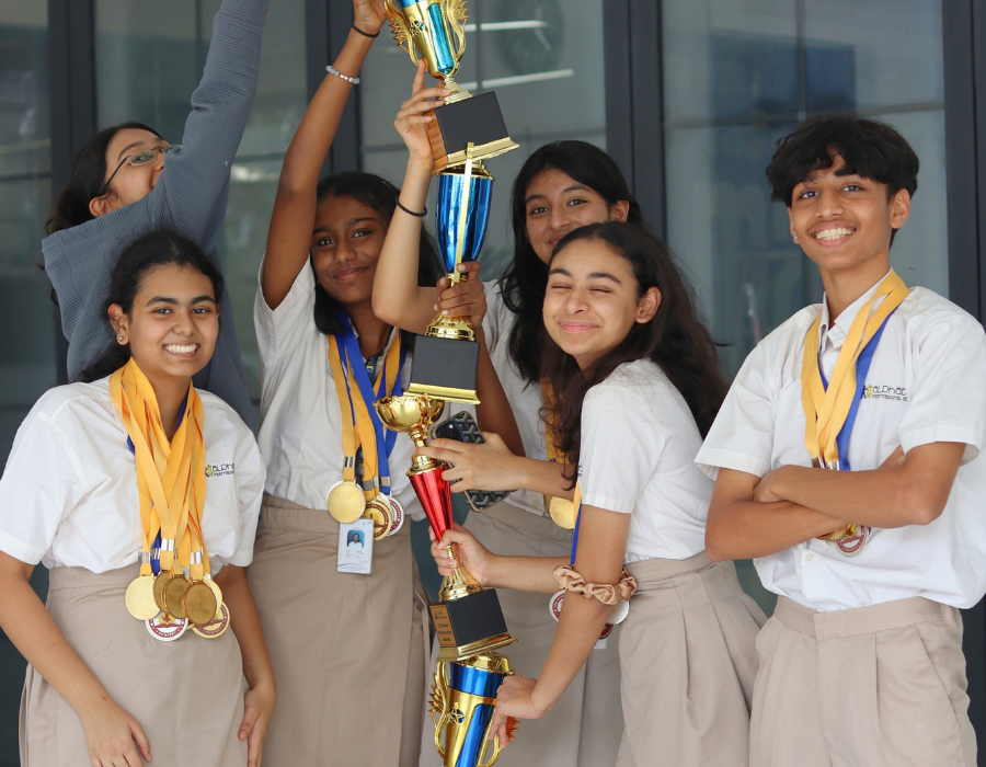 students holding stacked trophies